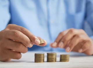 Mani che impilano monete, simbolo delle risorse economiche per la sanità.