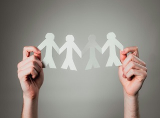 Mani che sorreggono sagome di persone collegate tra loro, simbolo di collaborazione globale in ambito sanitario.