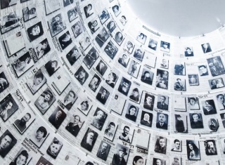 Muro con numerose fotografie di vittime della Shoah esposte come memoriale della memoria storica.