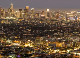 Panorama notturno di una grande città illuminata con skyline di grattacieli e quartieri urbani.