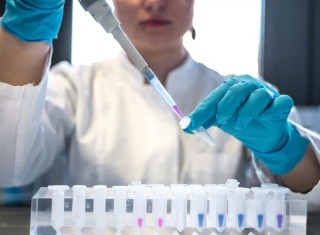 Tecnico di laboratorio che maneggia una provetta con liquido colorato